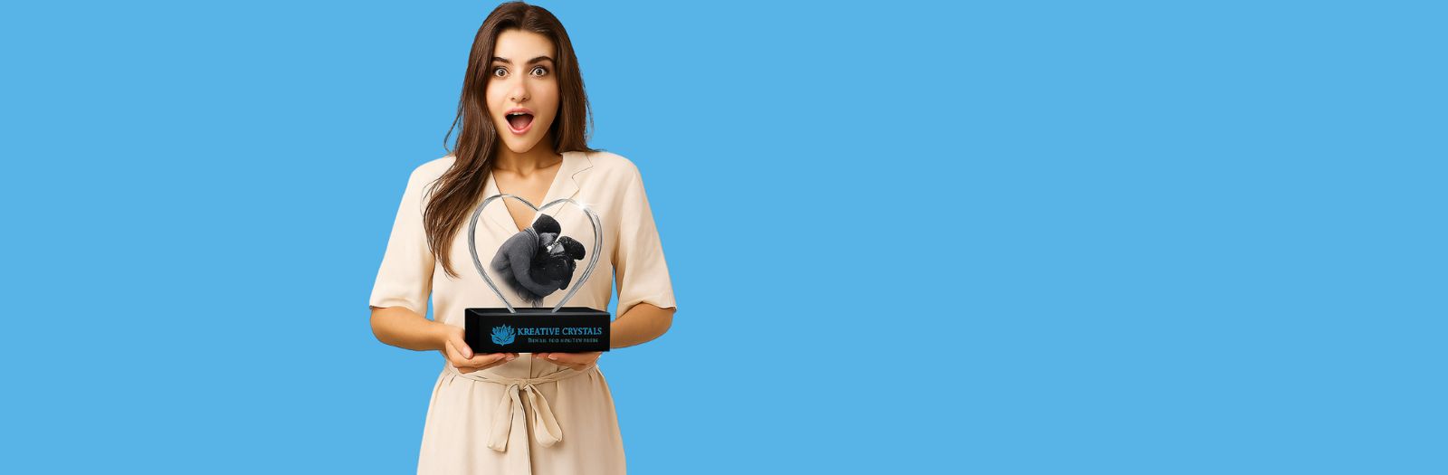 Woman holding a premium black crystal heart sculpture by Kreative Crystals against a blue background for luxury crystal gifting and home decor